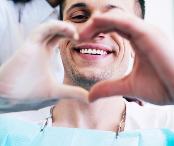 Patient making a heart around his smile