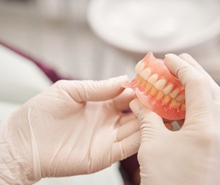 Dentist carefully holding a set of dentures