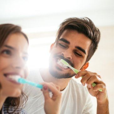 Man and woman brushing their teeth together