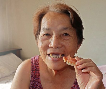 Lady smiles while showing removable denture