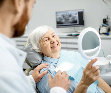 a patient checking her smile with her dentist’s mirror