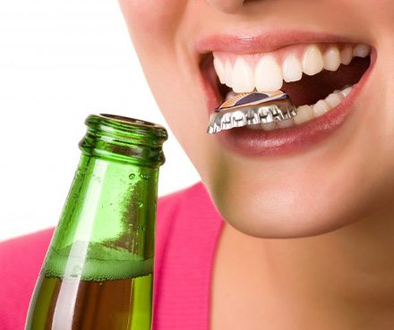 a person holding a bottle cap with their teeth