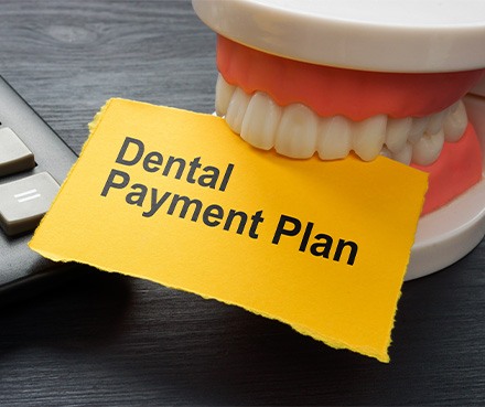 Fake teeth chomping a yellow paper that reads “Dental Payment Plan”