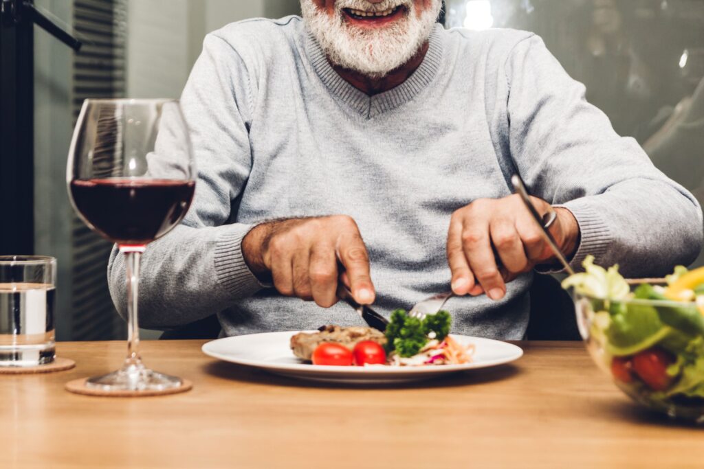 Mouth-down view of man with white beard eating dinner at a table